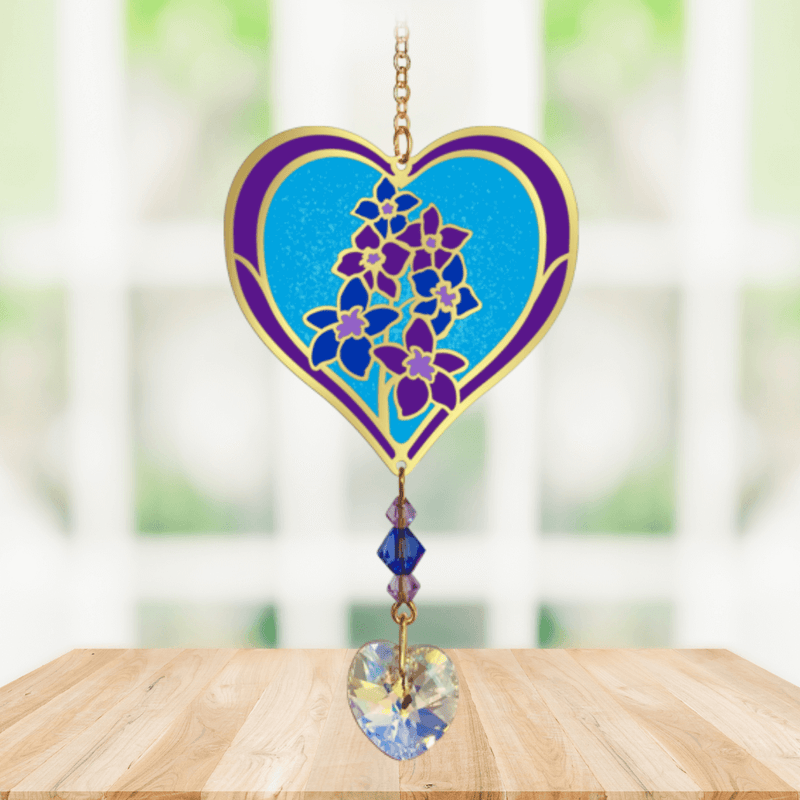 Heart-shaped Delphinium Crystal Suncatcher with purple blooms and dangling prism heart catching sunlight in a bright window

