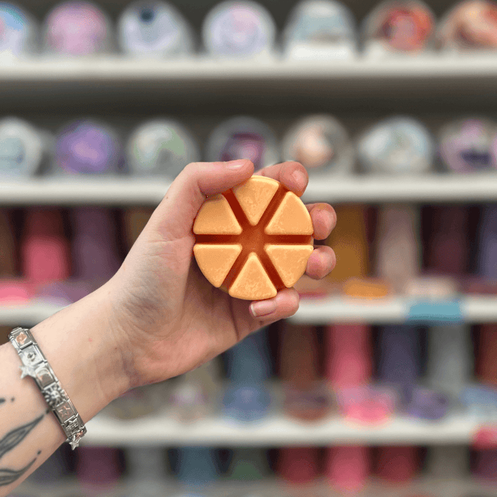 Desert Blossom wax melt segments held in hand with colourful wax melt display in the background