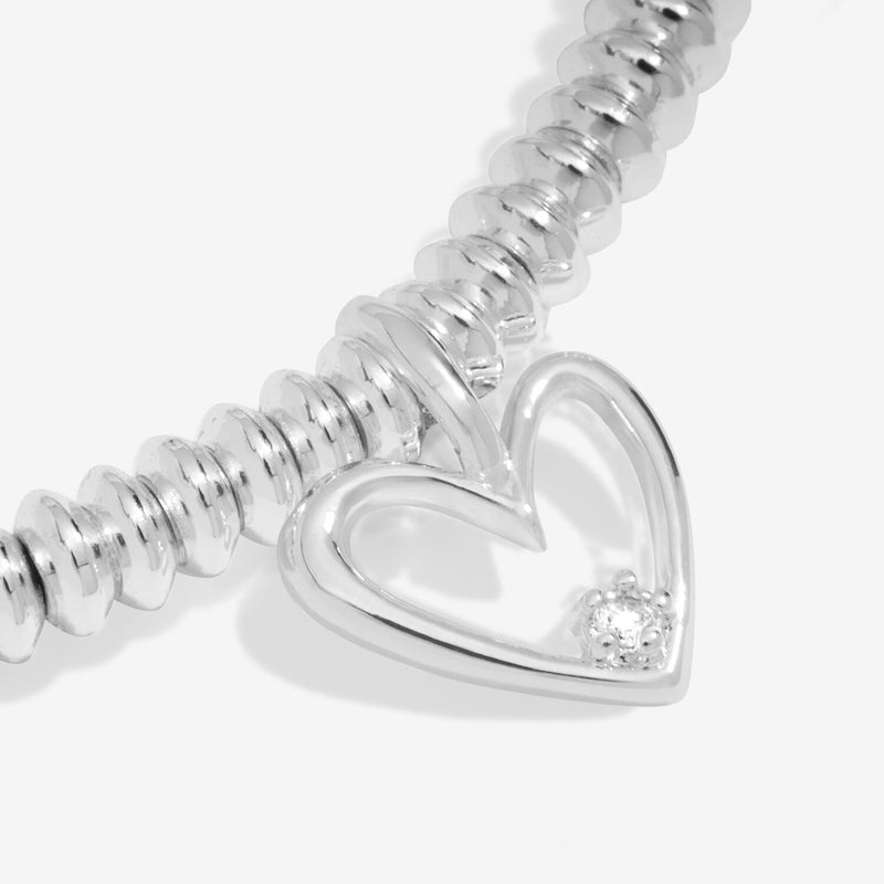 “Macro detail of diamond set in silver open‑heart charm”
