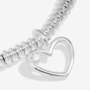 Macro view of diamond‑set heart charm on beaded bracelet