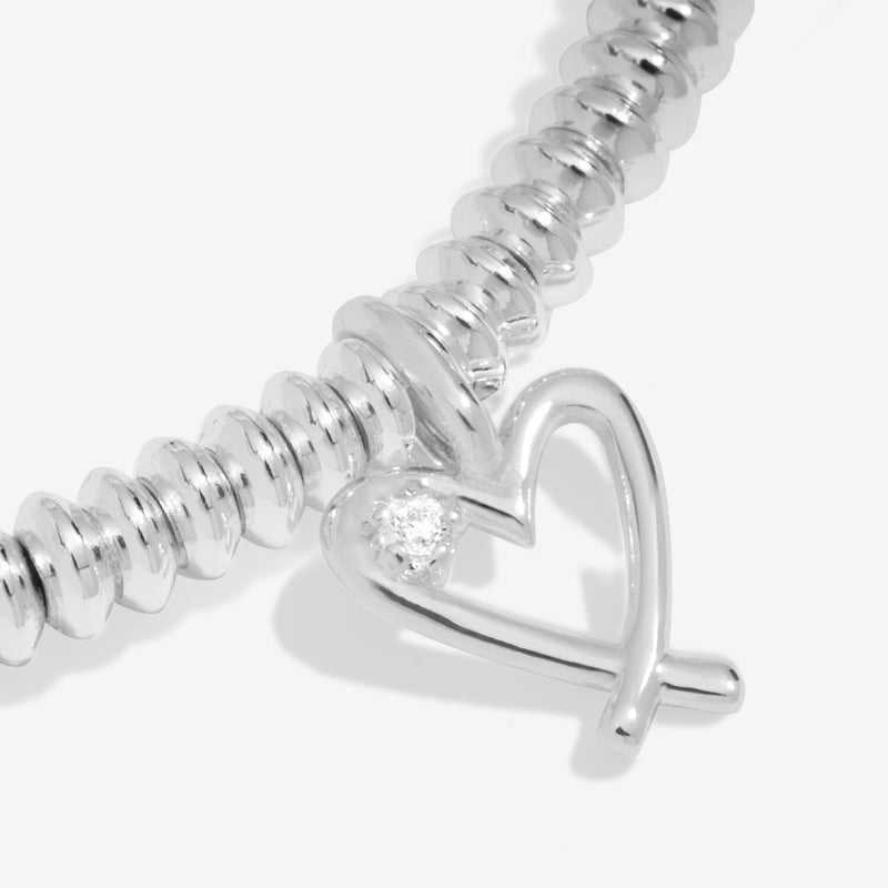 “Macro detail of diamond in heart charm – Lovely Sister bracelet”
