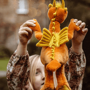 Back view of Diamonds orange dragon teddy from Bearhouse by Charlie Bears 2025 held outdoors, showing golden wings and spine detail