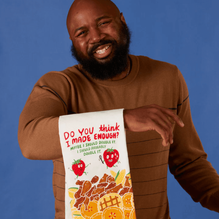 Model holding funny tea towel with Do you think I made enough? slogan and food artwork.
