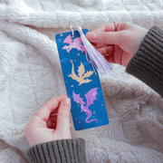 Dragons bookmark held in hands showing pink purple and gold dragon design