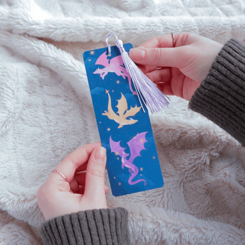 Dragons bookmark held in hands showing pink purple and gold dragon design