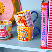 Eleanor Bowmer Breakfast Club mug displayed with colourful mugs and cookbooks