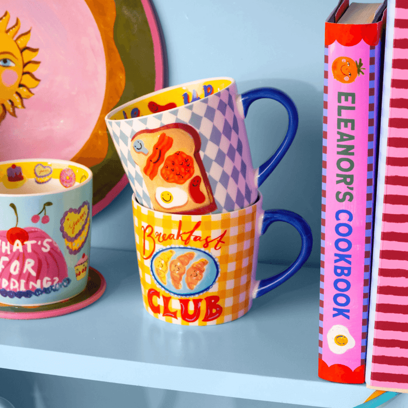 Eleanor Bowmer Breakfast Club mug displayed with colourful mugs and cookbooks