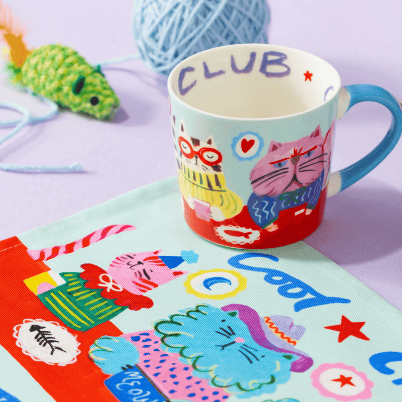 Eleanor Bowmer Cool Cat Club mug styled with colourful cat-themed accessories
