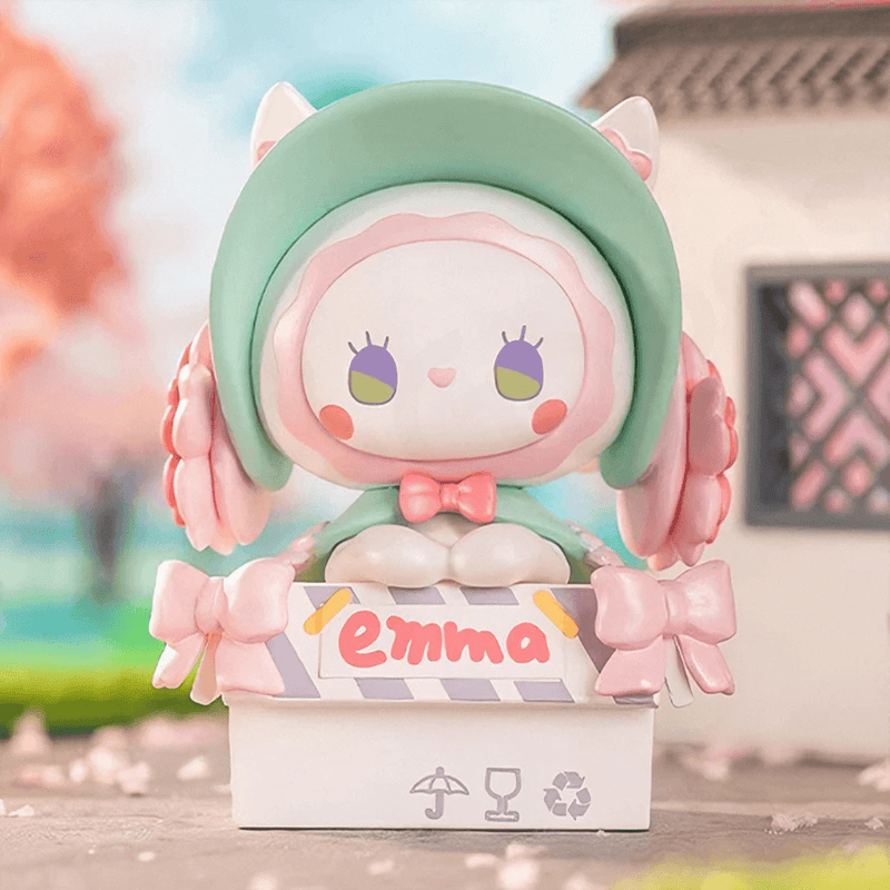 Homecoming Day figure in mint cat-eared bonnet perched on shipping box labelled “Emma”
