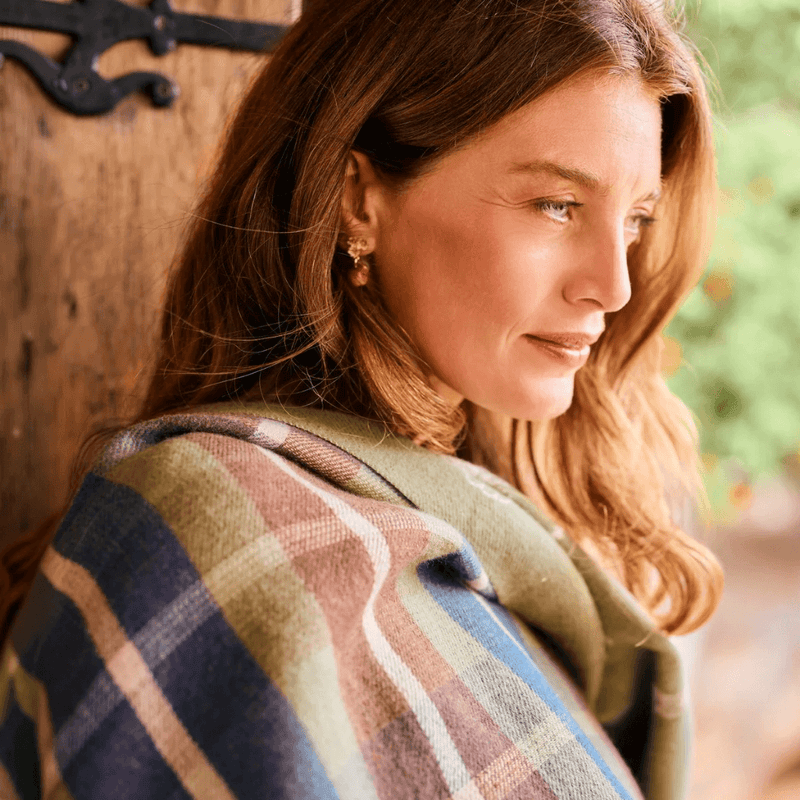 Woman wearing Fable England apple blossom earrings with a patterned autumn shawl