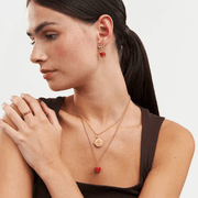Model wearing Fable England red apple earrings with layered gold necklaces