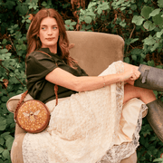Woman wearing Fable England embroidered bumblebee circle bag with a cream skirt and green top