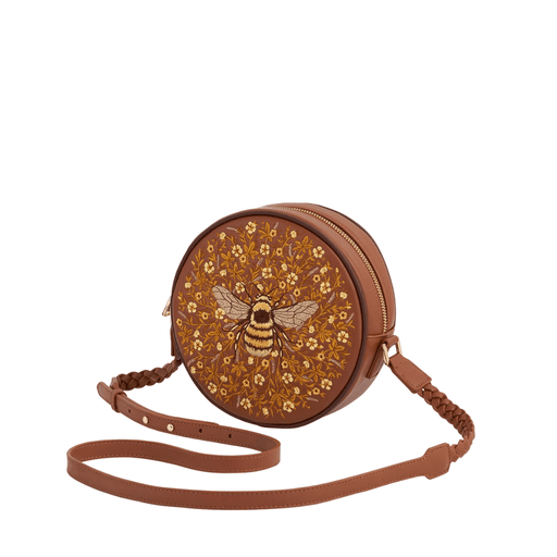 Angled view of Fable England tan round handbag showing bee embroidery, gold zip and braided strap