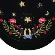 Close-up of golden stars, pink roses and blue-ribbon horseshoe embroidered on black velvet