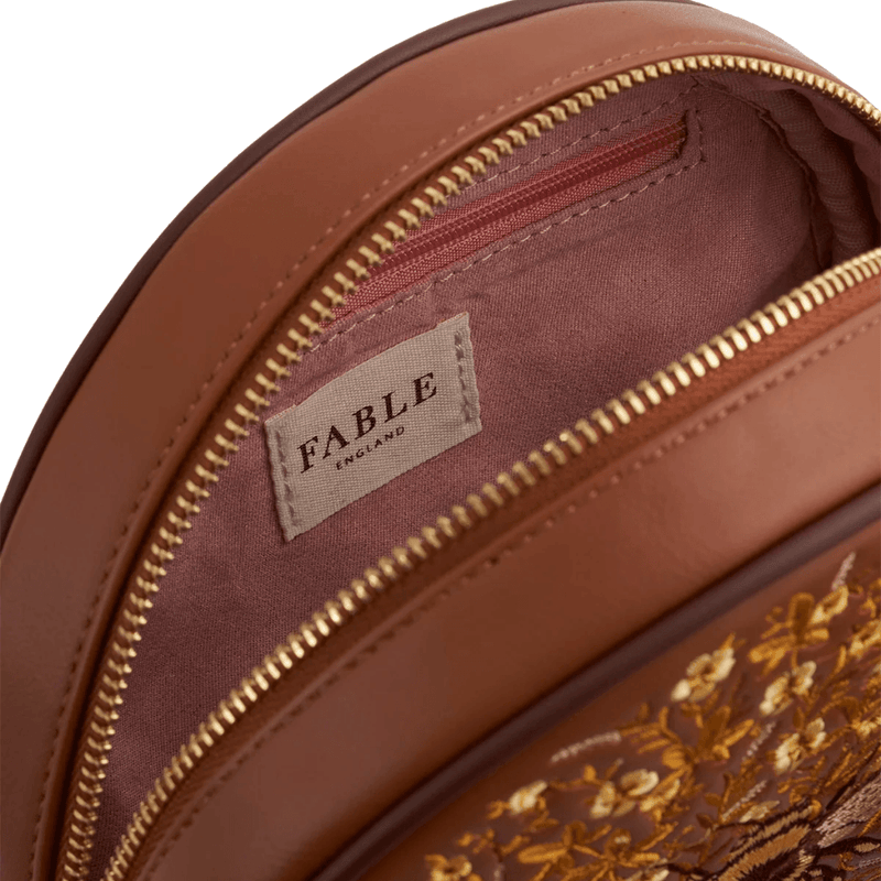 Interior of Fable England Bumble Circle Bag showing pink lining, internal zipped pocket and gold zip fastening