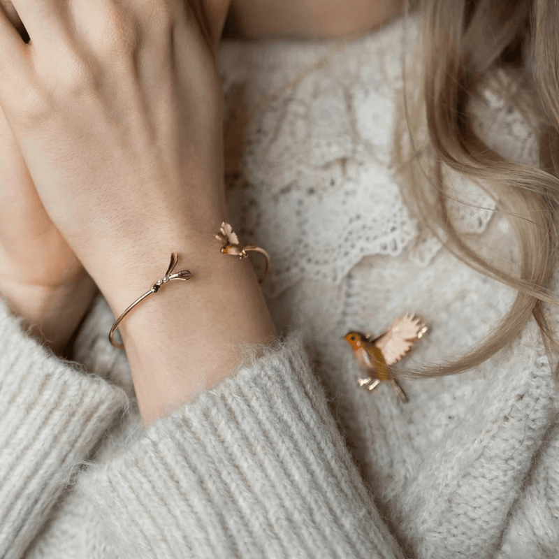 Fable England flying robin brooch worn on a cream knitted jumper with a matching bird bracelet