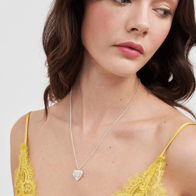 Model wearing Fable England silver forget-me-not heart locket necklace with a yellow lace top