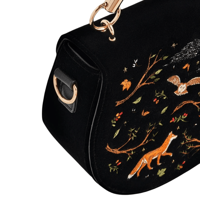 Close-up of fox and flying owl embroidery on Fable England black velvet bag with gold-toned strap hardware