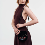 Model wearing Fable England Kate Celestial embroidered black saddle bag with a burgundy dress