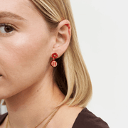 Close-up of Fable England pomegranate drop earring worn on the ear, showing its red blossom and fruit charm