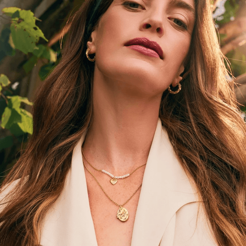 Model wearing Fable England gold robin and blackberry locket necklace layered with a shorter necklace