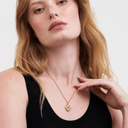 Model wearing Fable England robin and blackberry gold locket pendant with a black sleeveless top