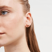 Model wearing a miniature gold robin stud earring by Fable England