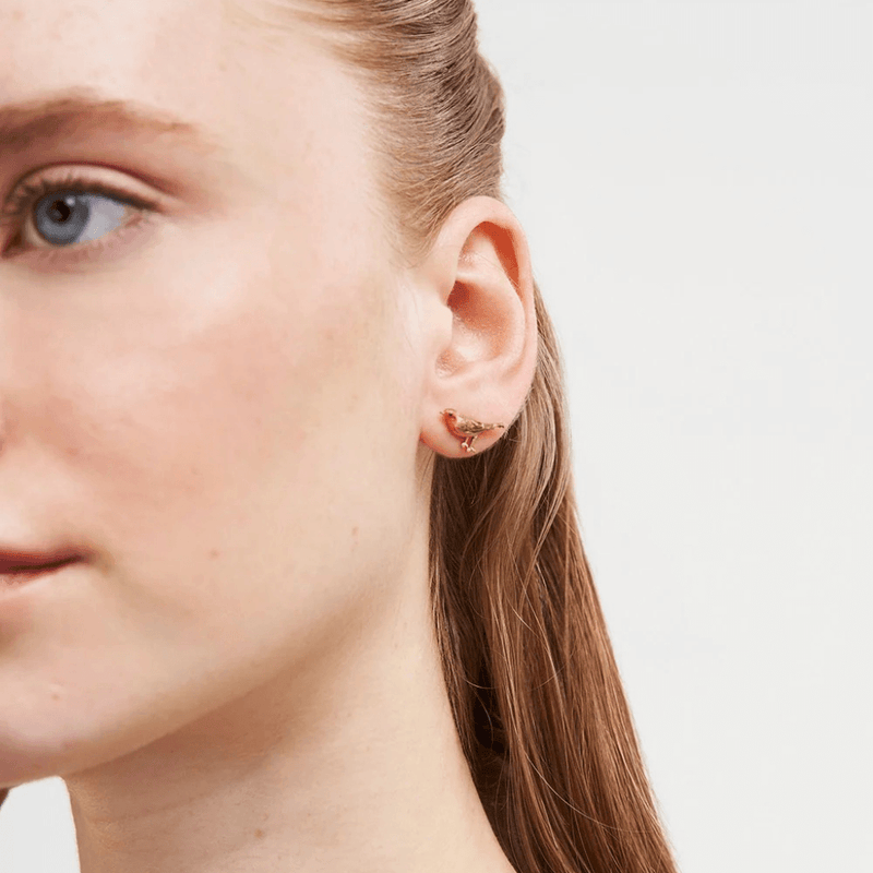 Model wearing a miniature gold robin stud earring by Fable England