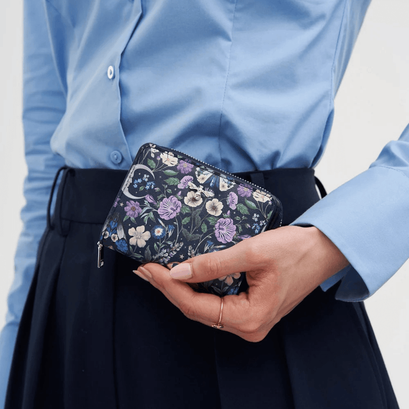 Model holding the Fable England Selene navy floral purse with moon and moth print
