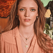 Model wearing Fable England gold swallow heart locket necklace layered with delicate jewellery