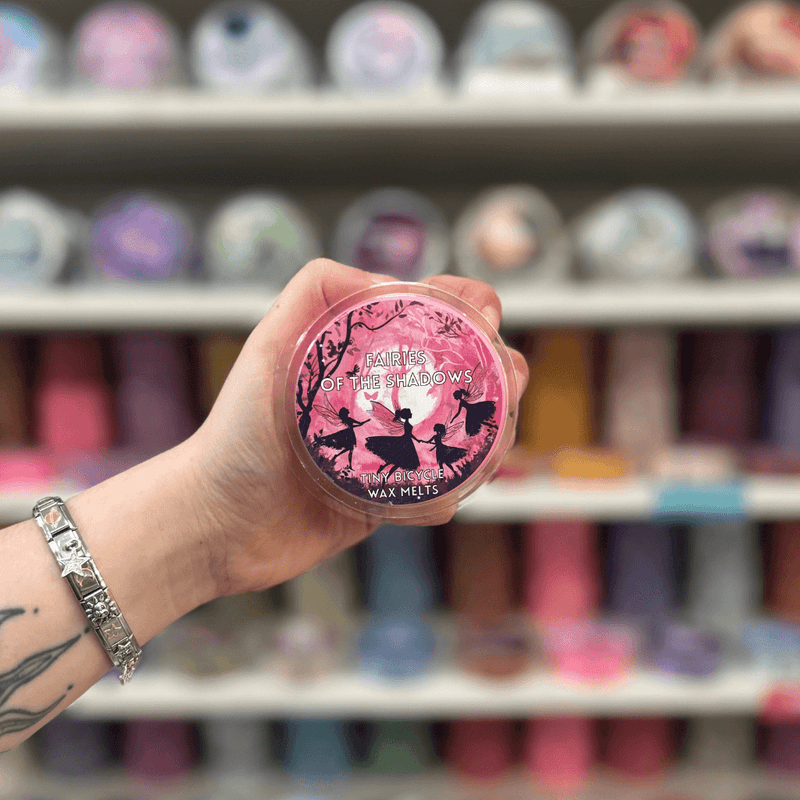 Fairies of the Shadows wax melt pot held in hand with colourful wax melt display in the background