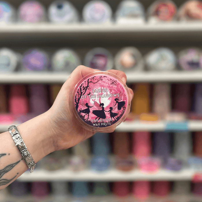 Fairies of the Shadows wax melt pot held in hand with colourful wax melt display in the background