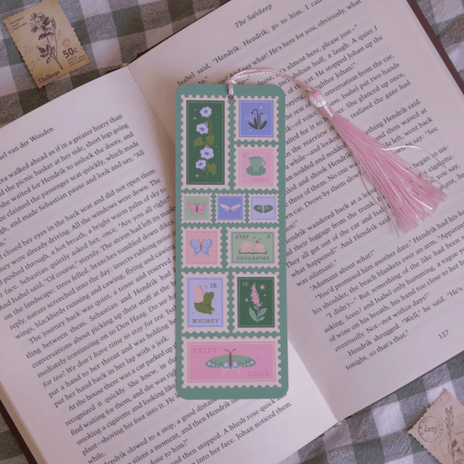 Fairycore Stamps bookmark with pink tassel inside an open book