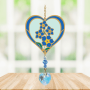 Heart-shaped Forget-Me-Not Crystal Suncatcher with blue blooms and sparkling prism heart catching sunlight in a bright window

