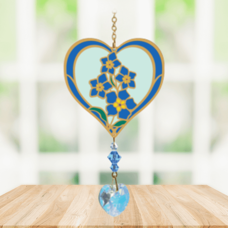 Heart-shaped Forget-Me-Not Crystal Suncatcher with blue blooms and sparkling prism heart catching sunlight in a bright window


