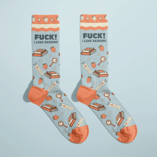 Pair of light blue women’s novelty crew socks with orange accents, stacks of books and bookmarks print, bold Fuck! I love reading text at the cuff.