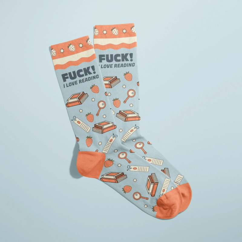 Overlapped light blue women’s crew socks with orange heels and toes, books, strawberries and magnifying glass icons, slogan Fuck! I love reading.