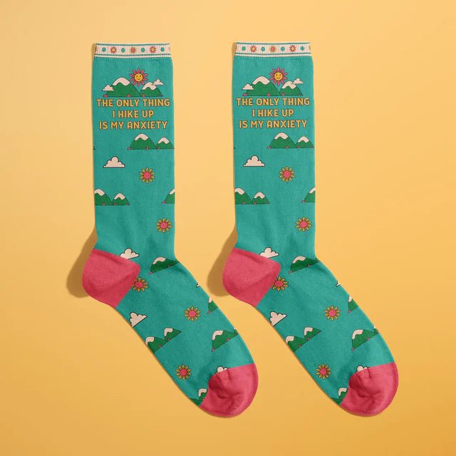 Laid flat novelty socks with hiking mountain pattern and humorous anxiety message, perfect for quirky gift-giving.

