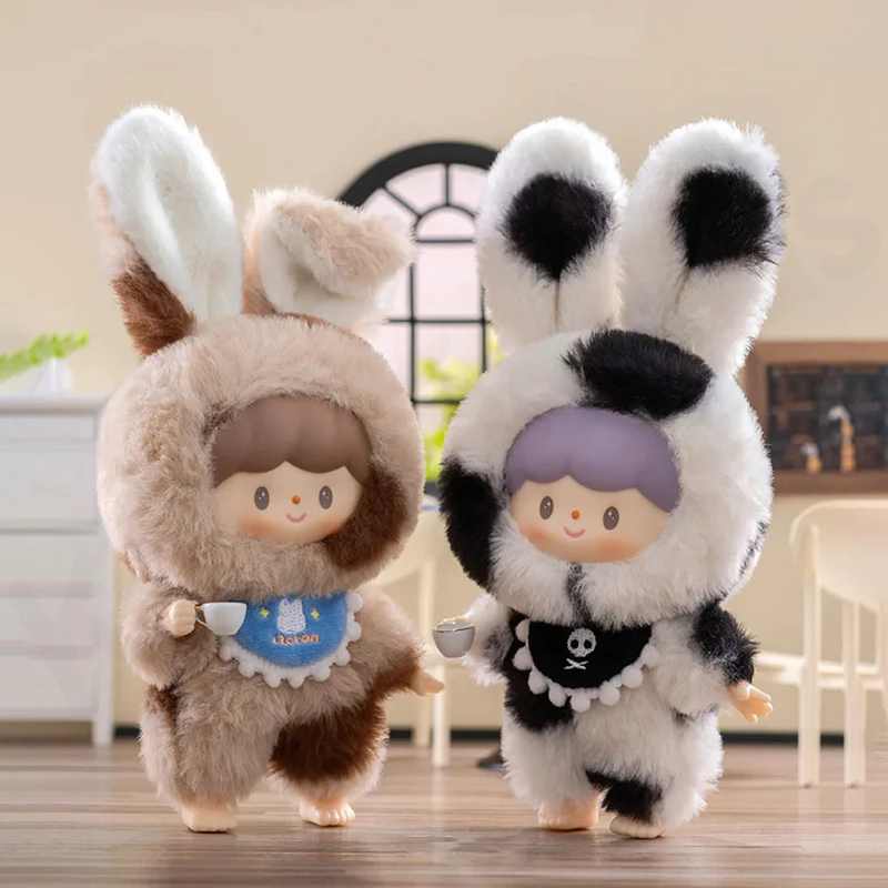 Cookie Bunny (mottled brown) and Oli Bunny (monochrome cow-print) with playful bibs	