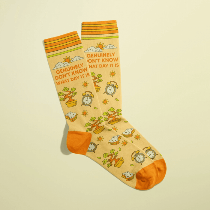 Overlapped butter-yellow women’s crew socks with orange heels and toes, bonsai plants, clocks and suns, slogan Genuinely don’t know what day it is.