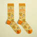 Pair of butter-yellow women’s novelty crew socks with orange accents and playful bonsai, clock and sun icons, text Genuinely don’t know what day it is.
