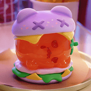 “Burger” variant—glossy orange bun bear with purple sesame top and melty cheese.
