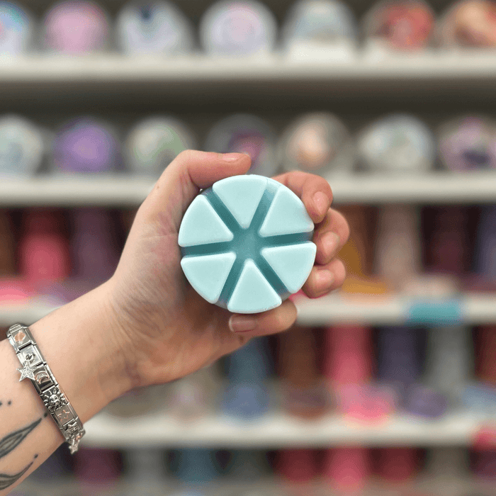 Ghost Flower wax melt segments held in hand with colourful wax melt display in the background