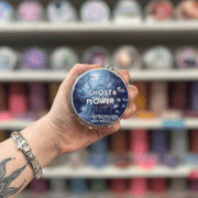 Ghost Flower wax melt pot held in hand with colourful wax melt display in the background