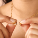Hands pulling apart the gold magnetic heart pendant to show the magnetic clasp