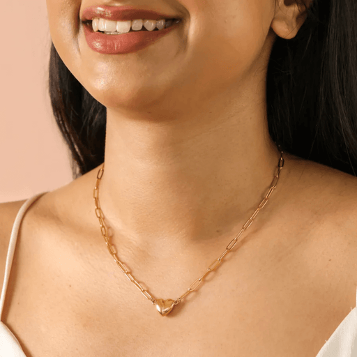 Gold magnetic heart pendant necklace worn on a model, paperclip chain detail