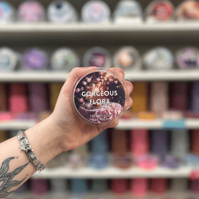 Gorgeous Flora wax melt pot held in hand with colourful wax melt display in the background