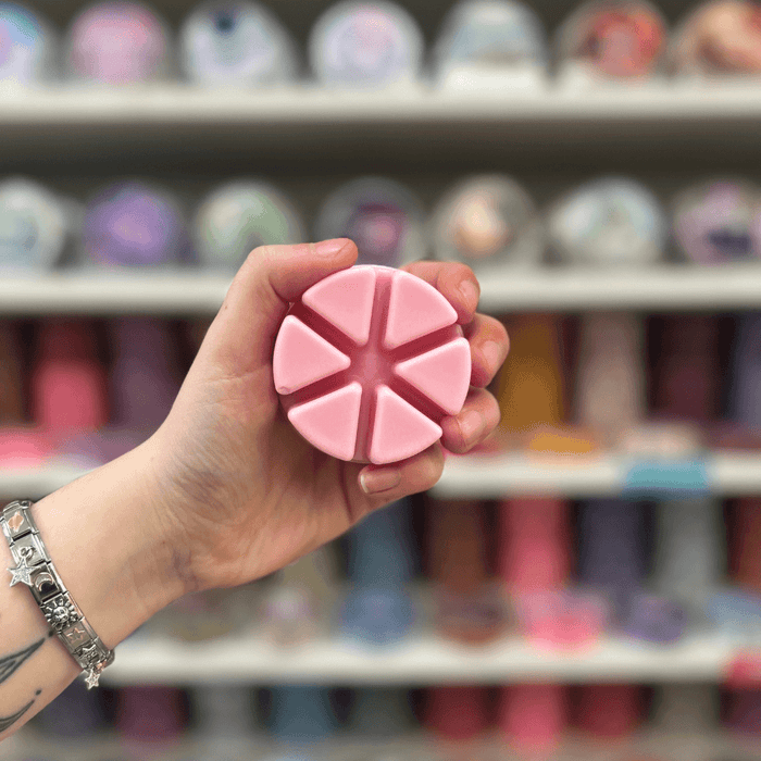 Gorgeous Flora wax melt segments held in hand with colourful wax melt display in the background