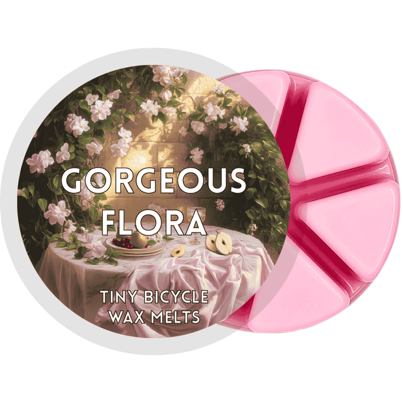 Pink Gorgeous Flora wax melt with vintage-style floral table scene featuring jasmine and pear slices.