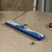 Handpainted ceramic Great Wave incense holder with stick incense on a woven surface